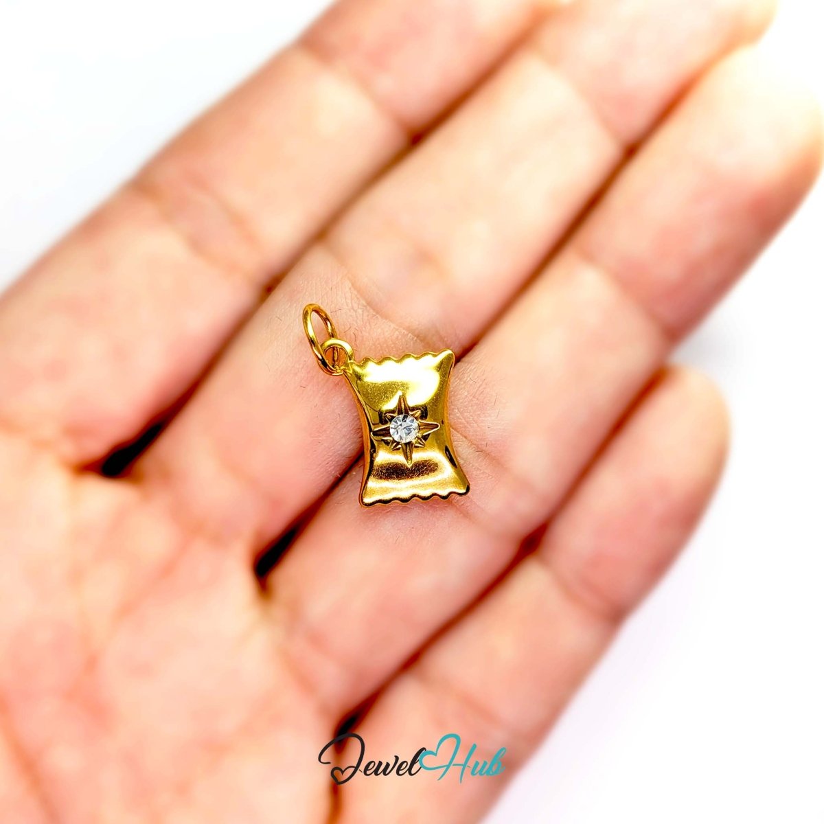 Wrapped sweet charm in gold stainless steel with a clear crystal - held in the hand for scale - JewelHub