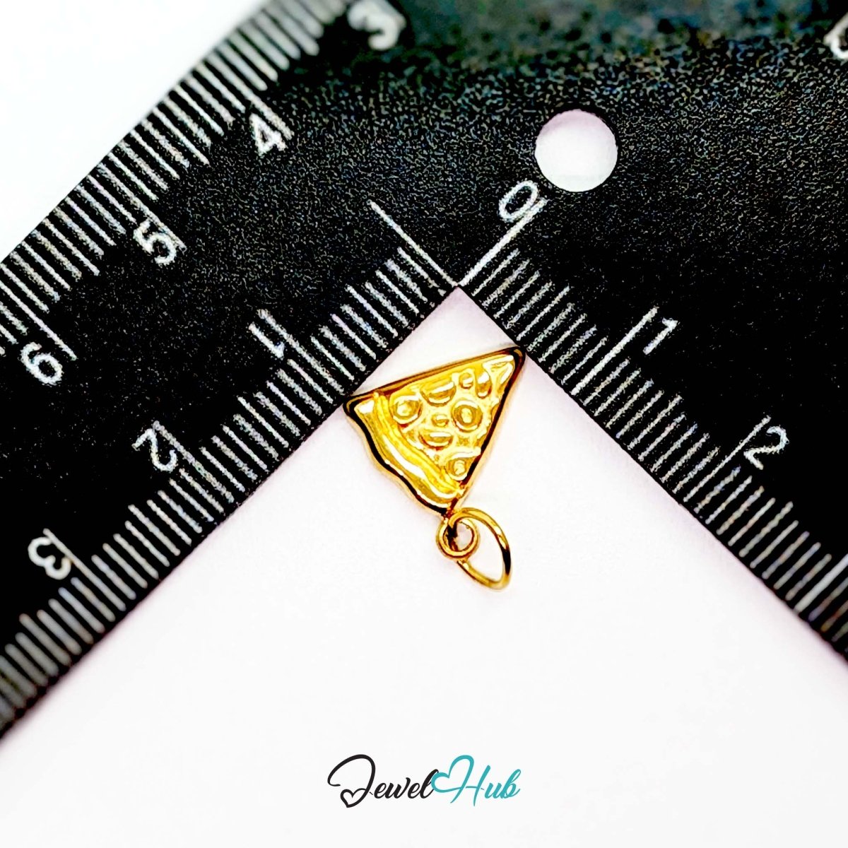 Embossed pizza slice charm in gold stainless steel - beside a ruler for scale - JewelHub