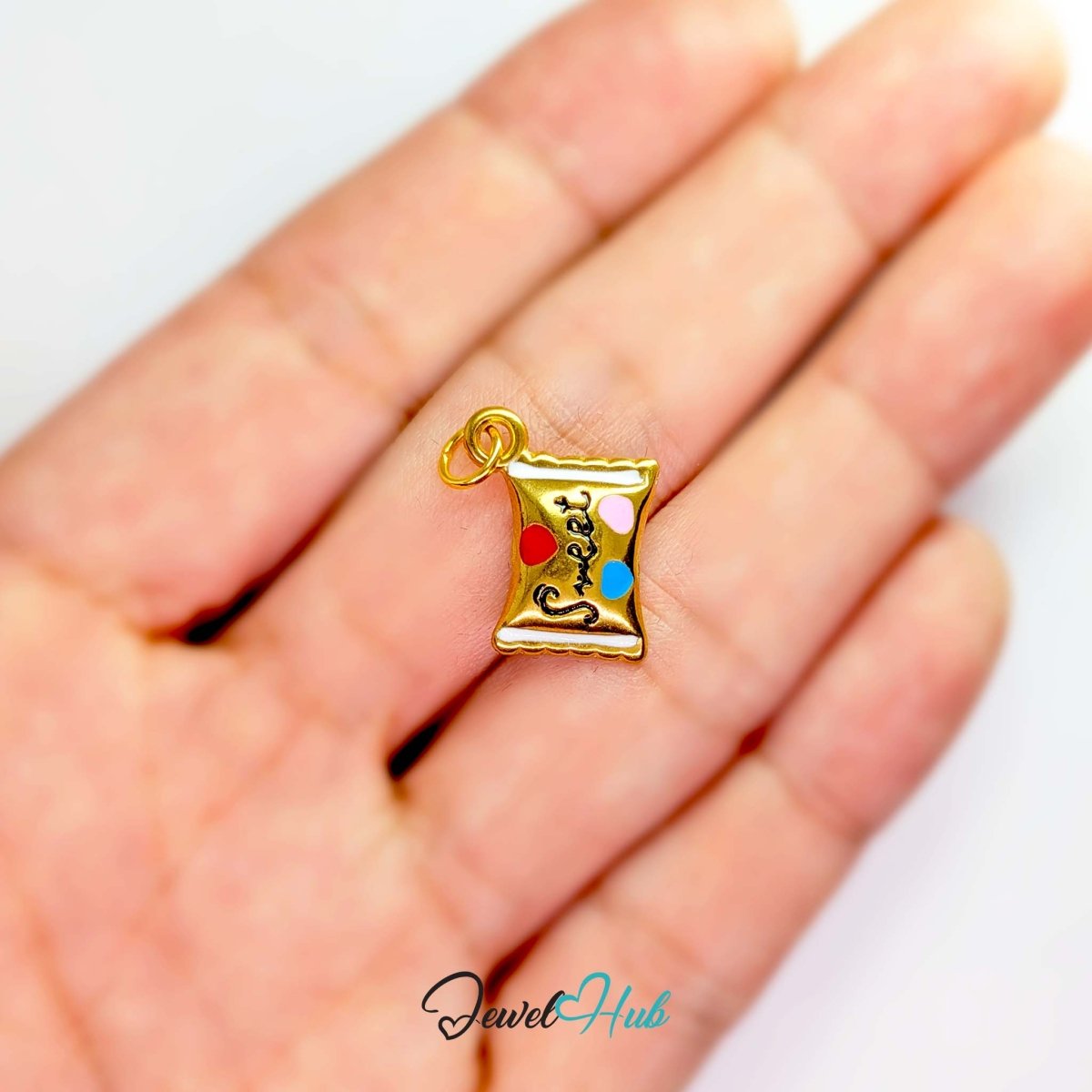 Enamel wrapped sweet charm in gold stainless steel - held in the hand for scale - JewelHub