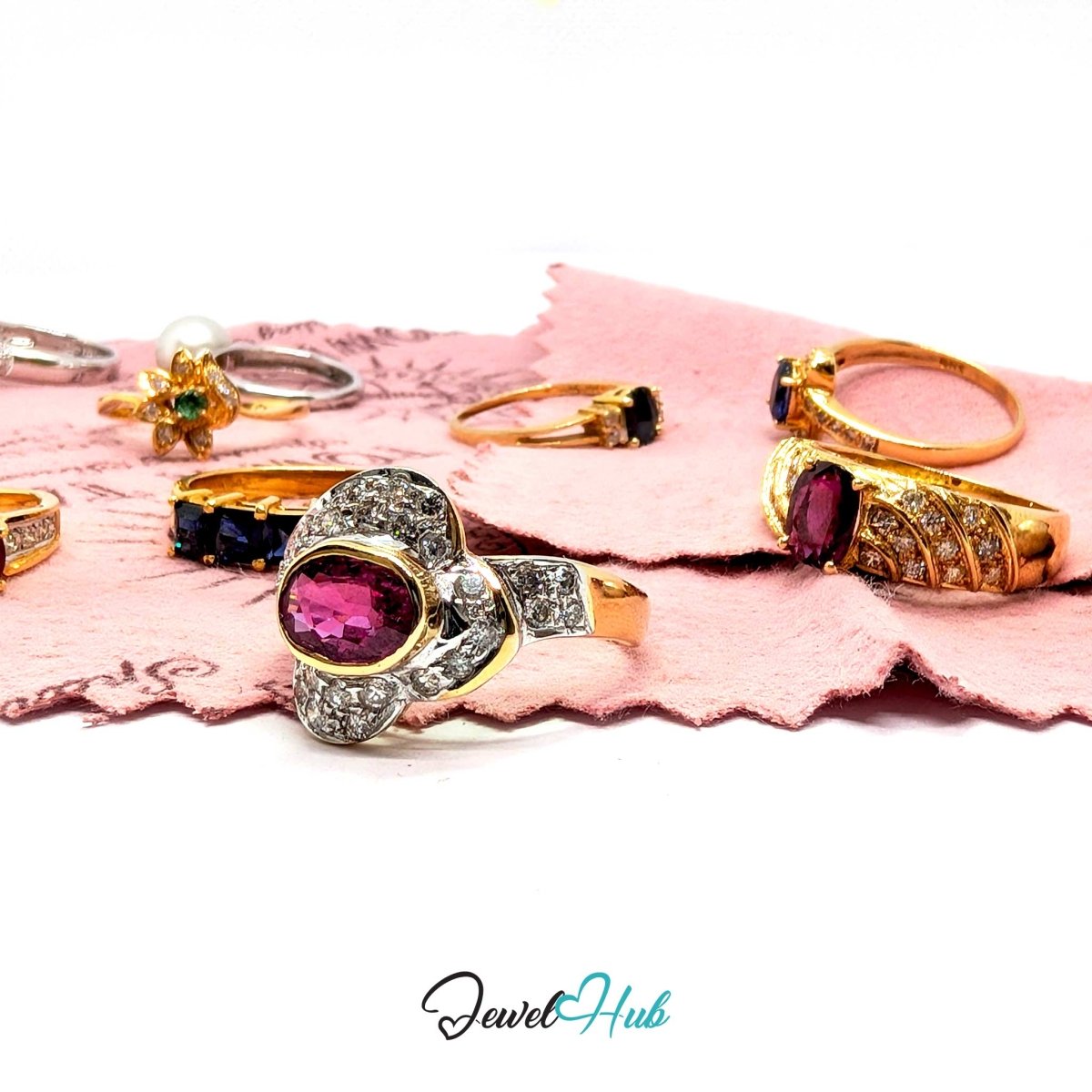 Gold rings set with pink tourmaline, sapphire, diamonds and pearl resting on the pink Town Talk gold polishing cloth.