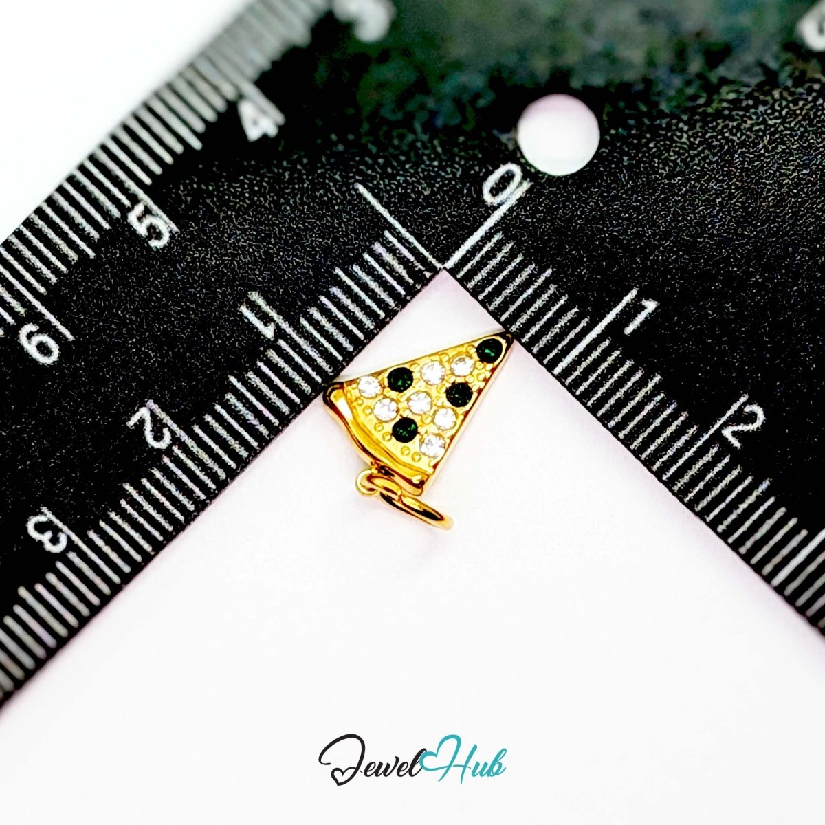 Pizza slice charm in gold stainless steel set with clear and dark green crystals - beside a ruler for scale - JewelHub