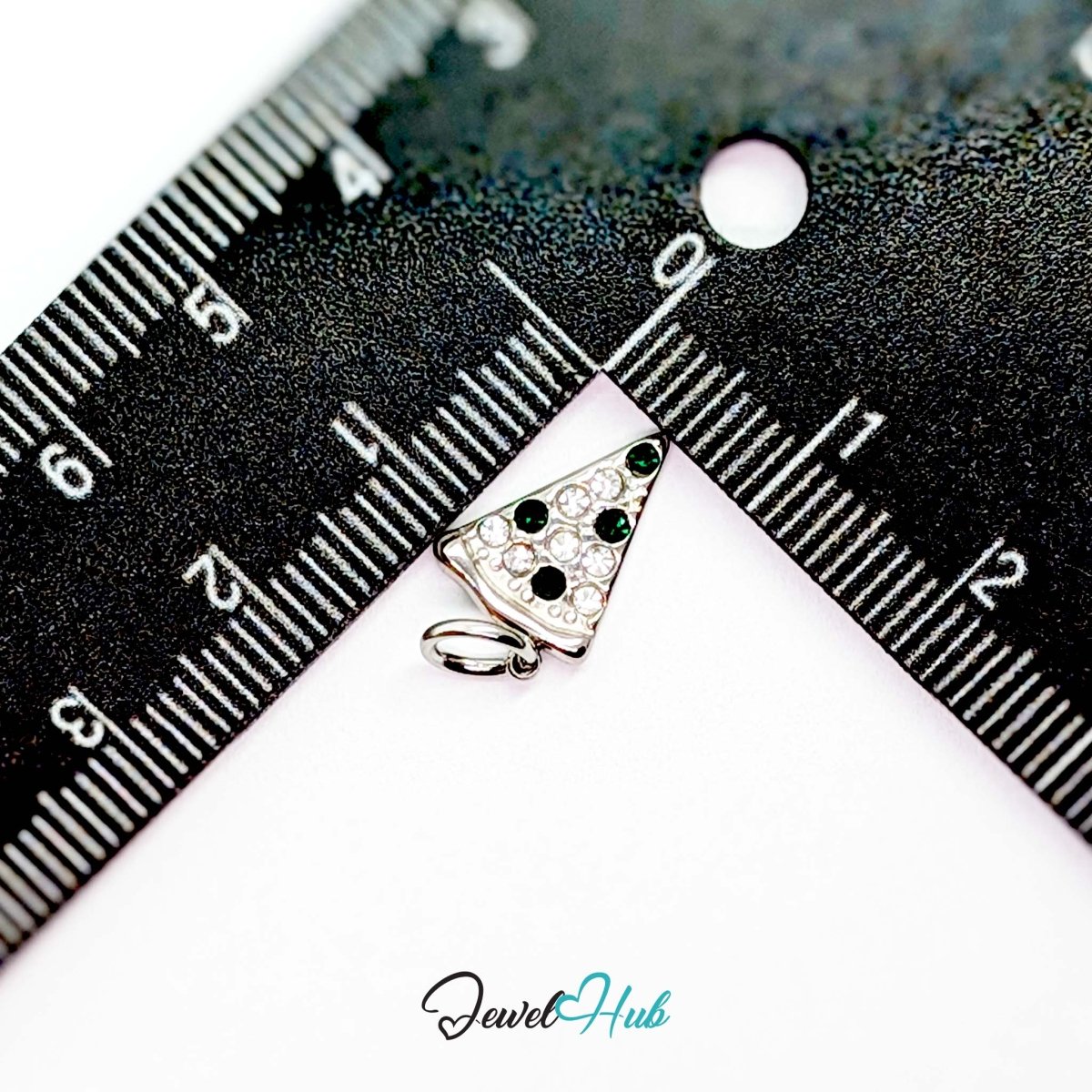 Pizza slice charm in silver stainless steel set with clear and dark green crystals - beside a ruler for scale - JewelHub