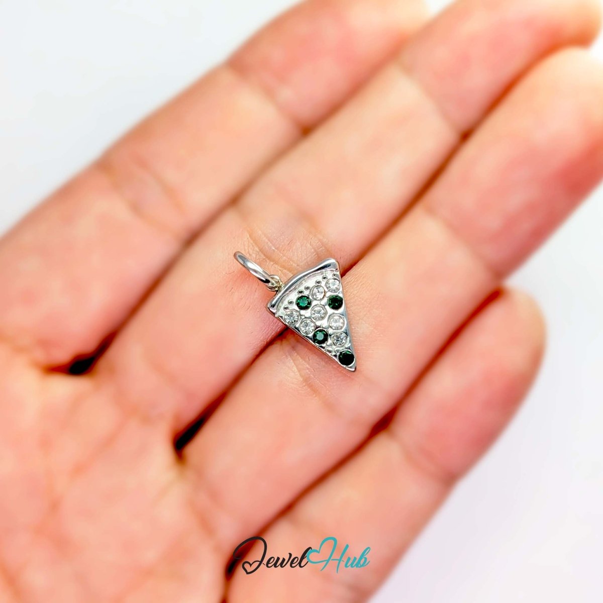 Pizza slice charm in silver stainless steel set with clear and dark green crystals - held in the hand for scale - JewelHub