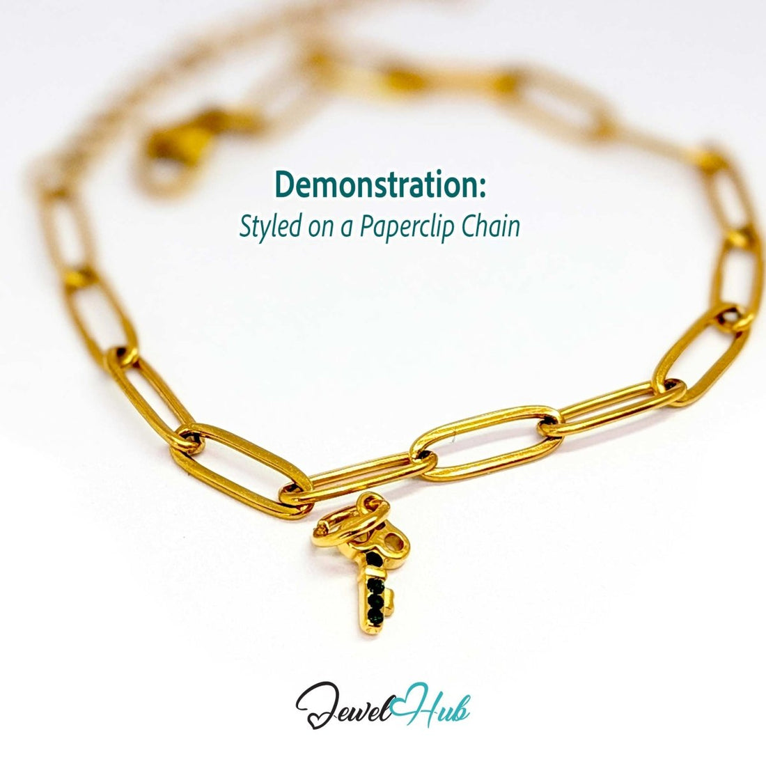 Mini key charm in gold stainless steel with four green stones - styled on a gold paperclip chain bracelet - JewelHub