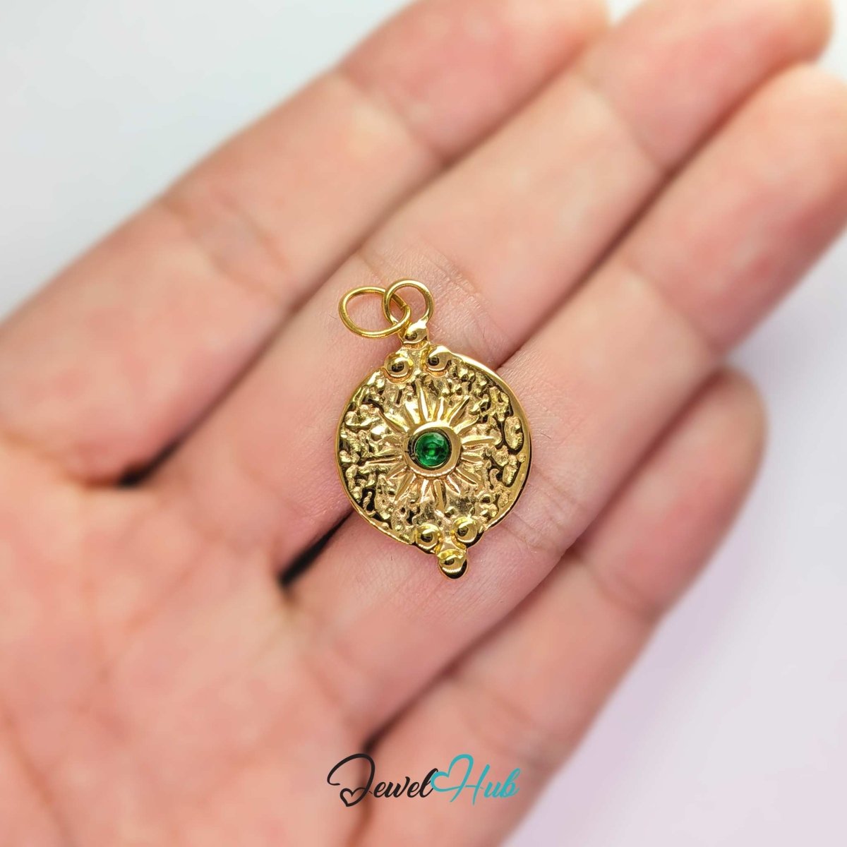 Rosette medallion charm in gold stainless steel with a green gem - held in the hand for scale - JewelHub