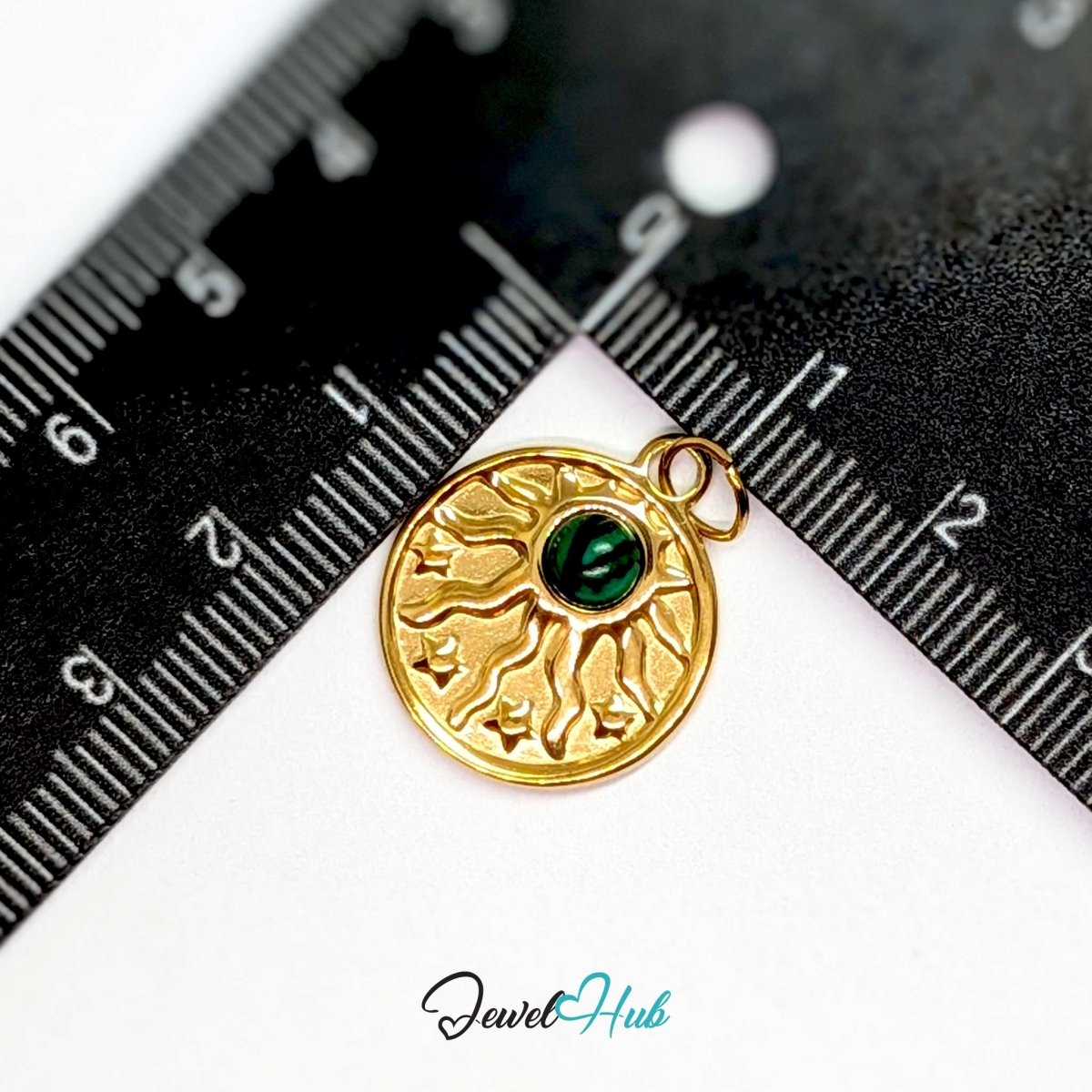 Sun and stars charm in gold stainless steel with a green stone - beside a ruler for scale - JewelHub