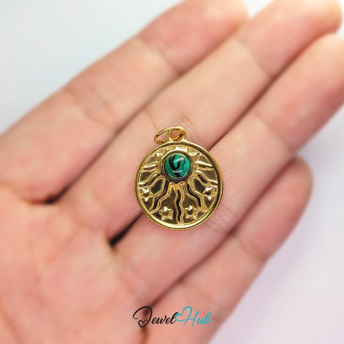 Sun and stars charm in gold stainless steel with a green stone - held in the hand for scale - JewelHub