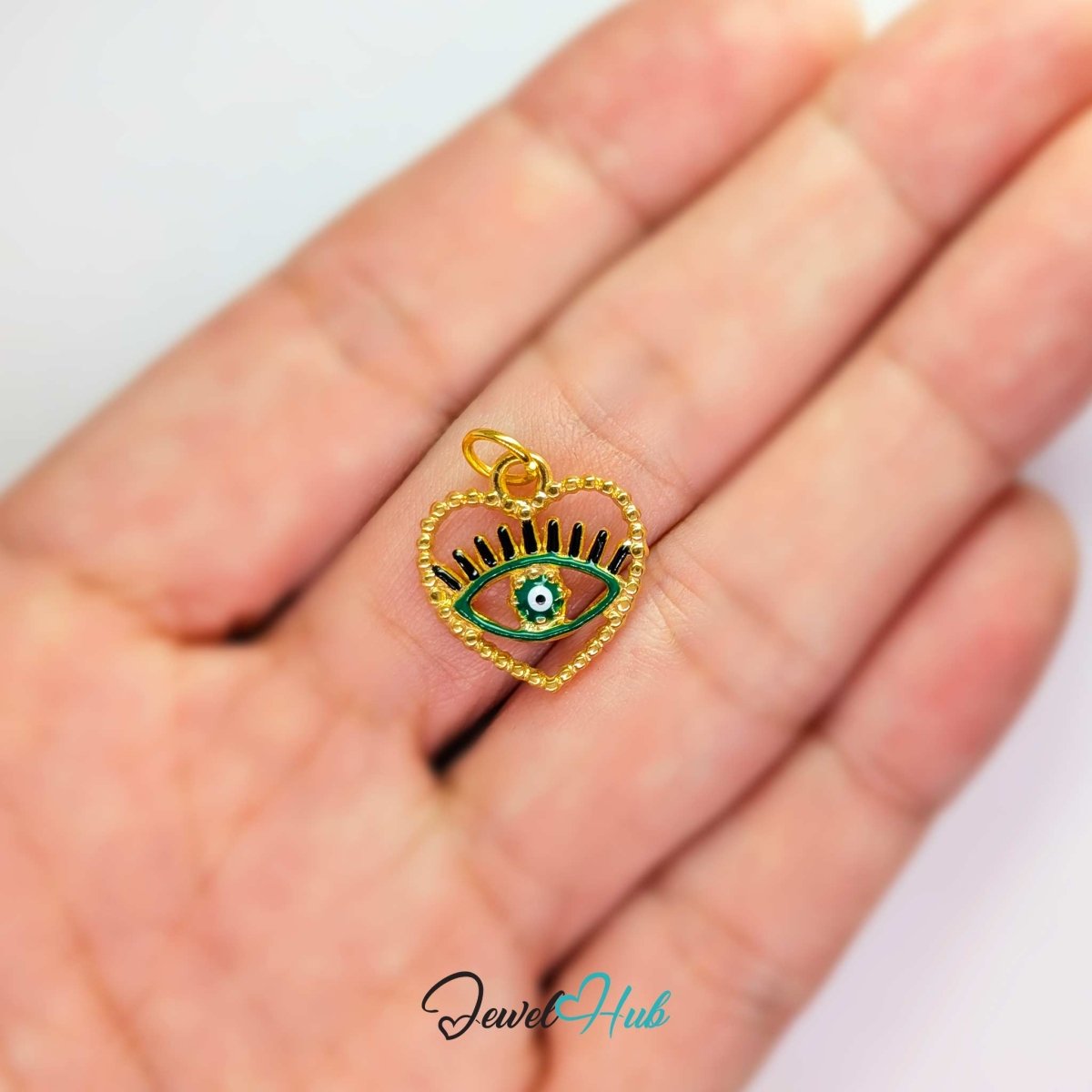 Green Hollow Evil Eye charm, gold stainless steel with enamel, held in the hand to show its size - JewelHub