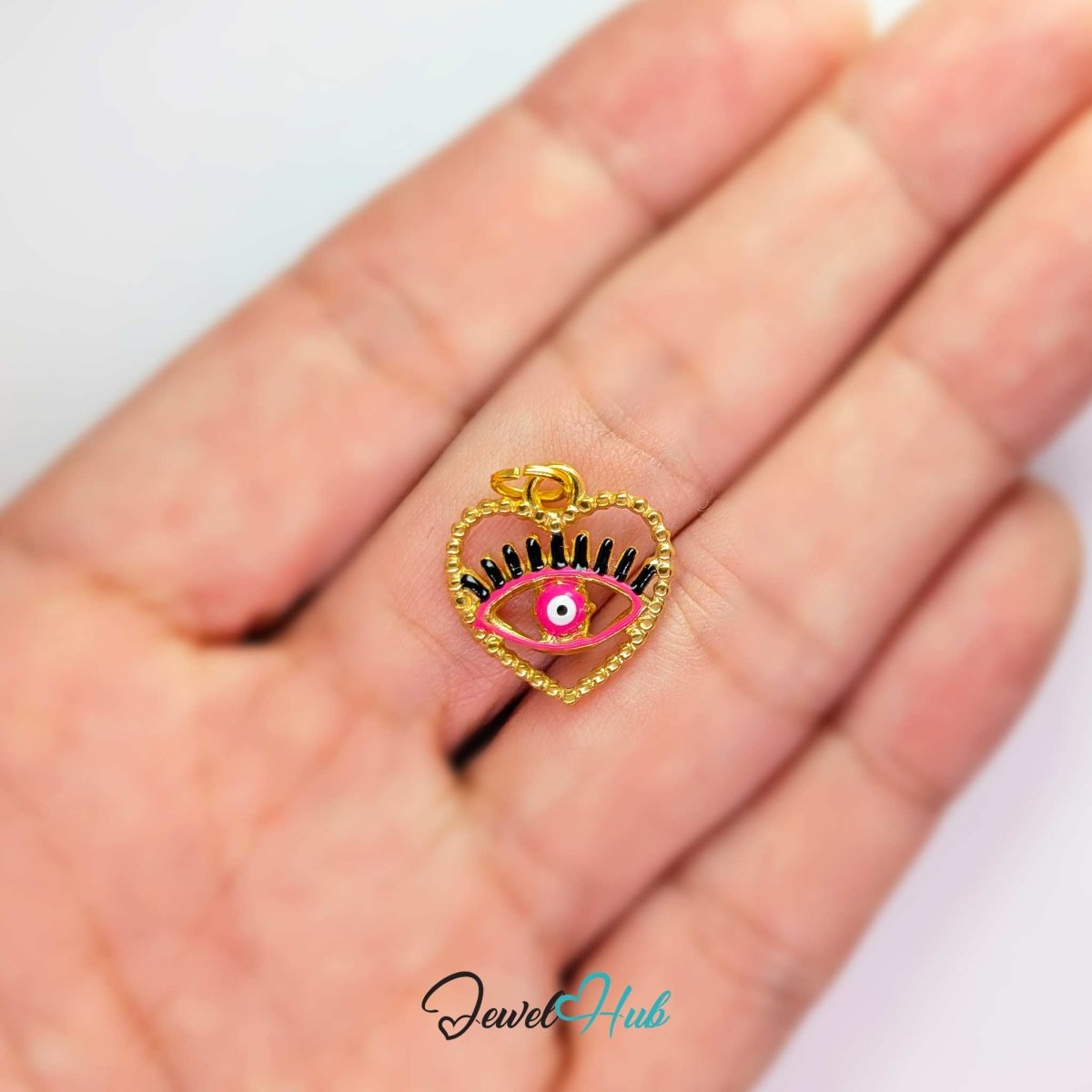 Pink Hollow Evil Eye charm, gold stainless steel with enamel, held in the hand to show its size - JewelHub
