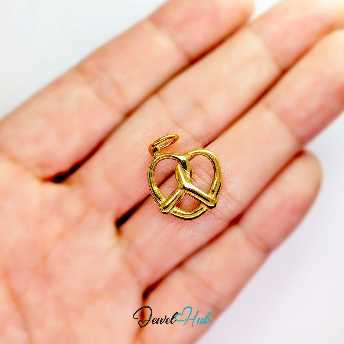 Large openwork pretzel charm in gold stainless steel - held in the hand for scale - JewelHub