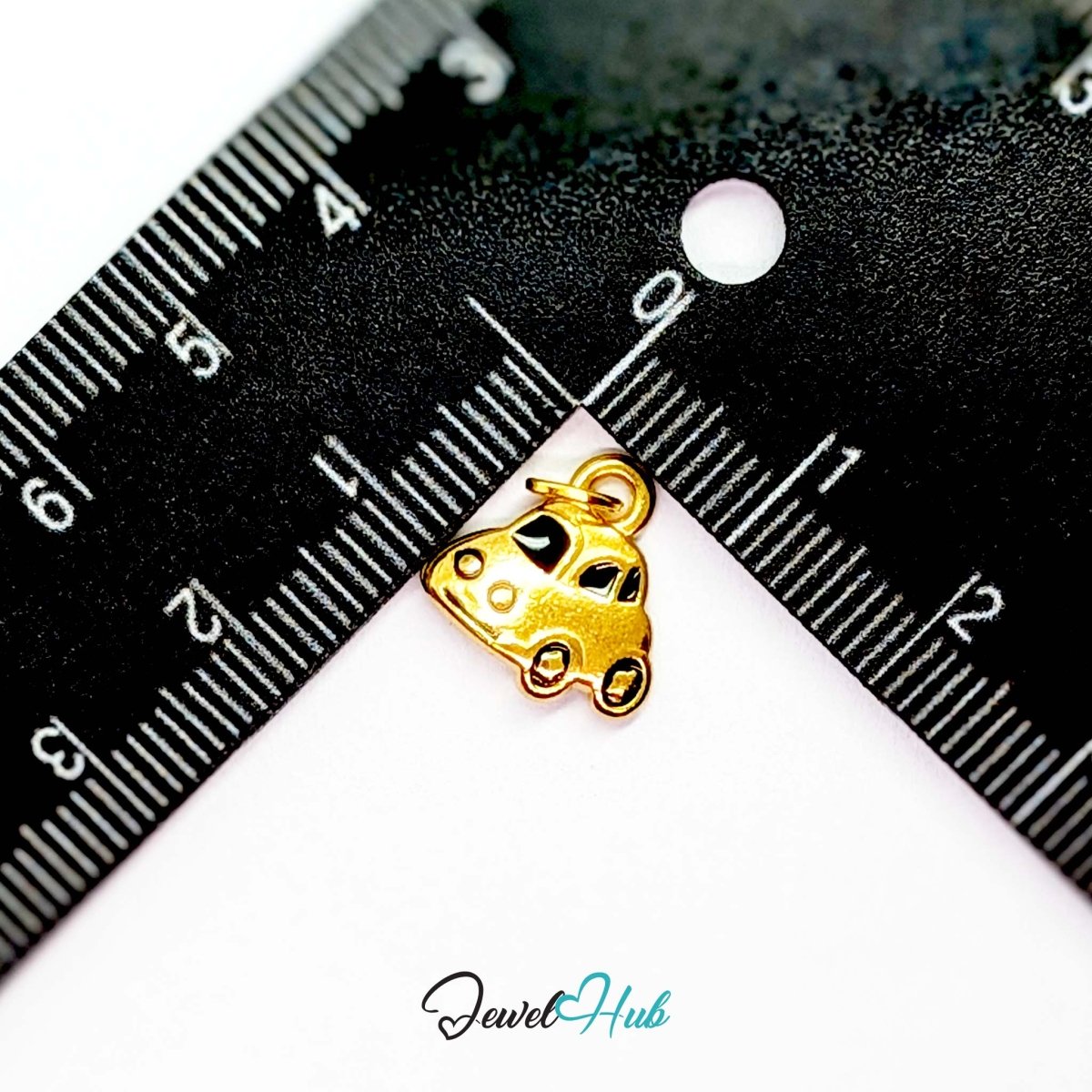 Little car charm in gold stainless steel with black enamel - beside a ruler for scale - JewelHub