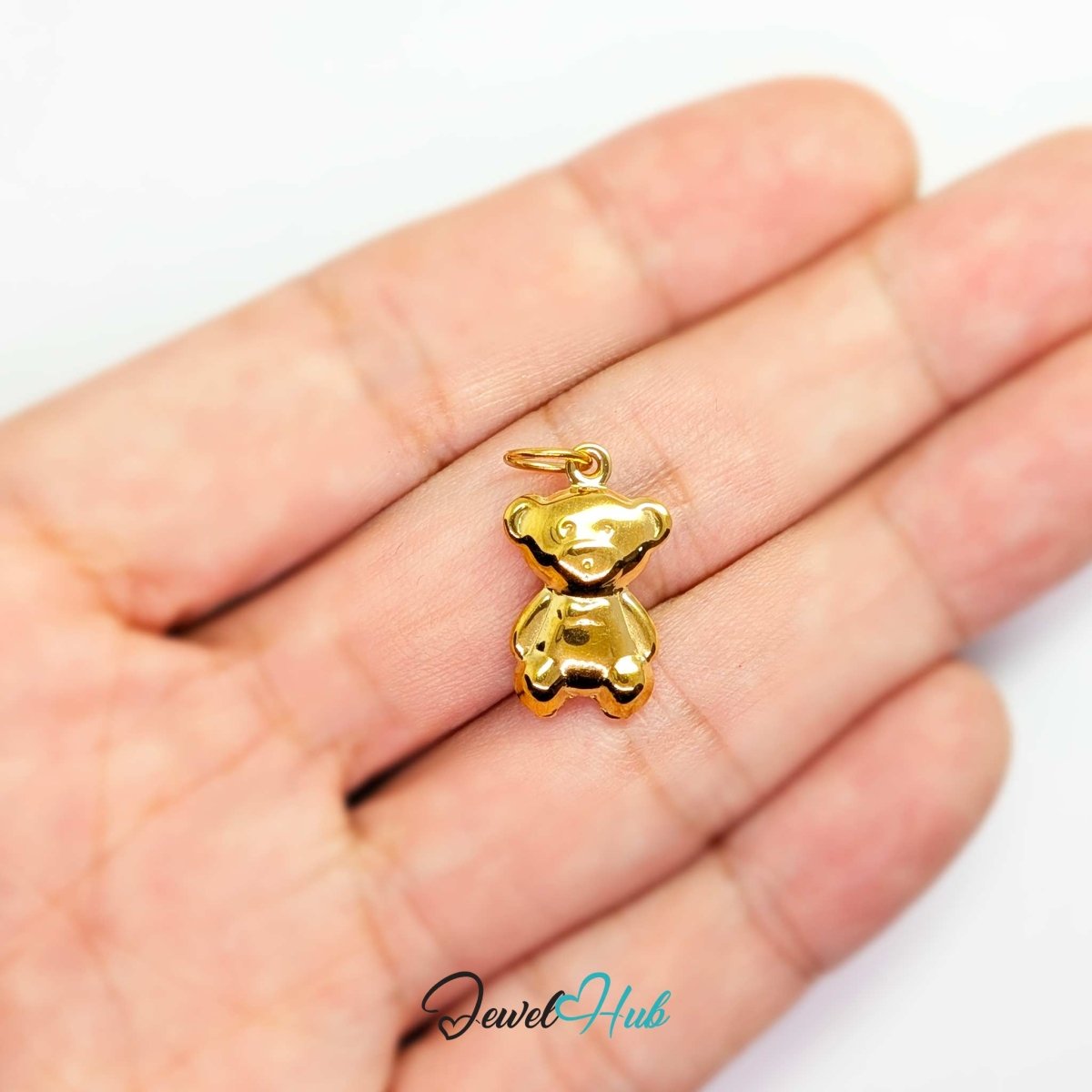 Gold Mini Classic Bear charm held in the hand to show its size against a fingertip - JewelHub