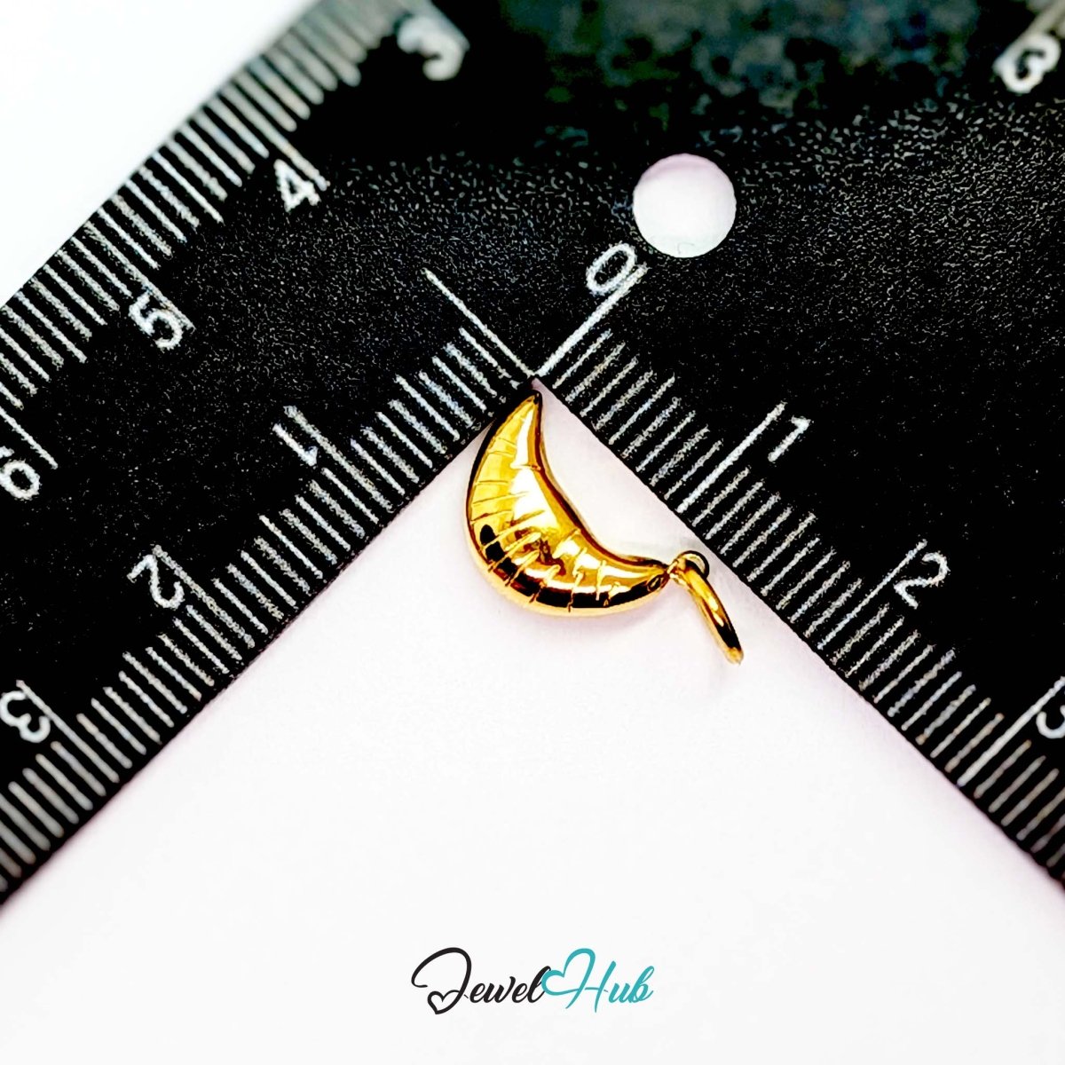 Mini croissant charm in gold stainless steel - beside a ruler for scale - JewelHub