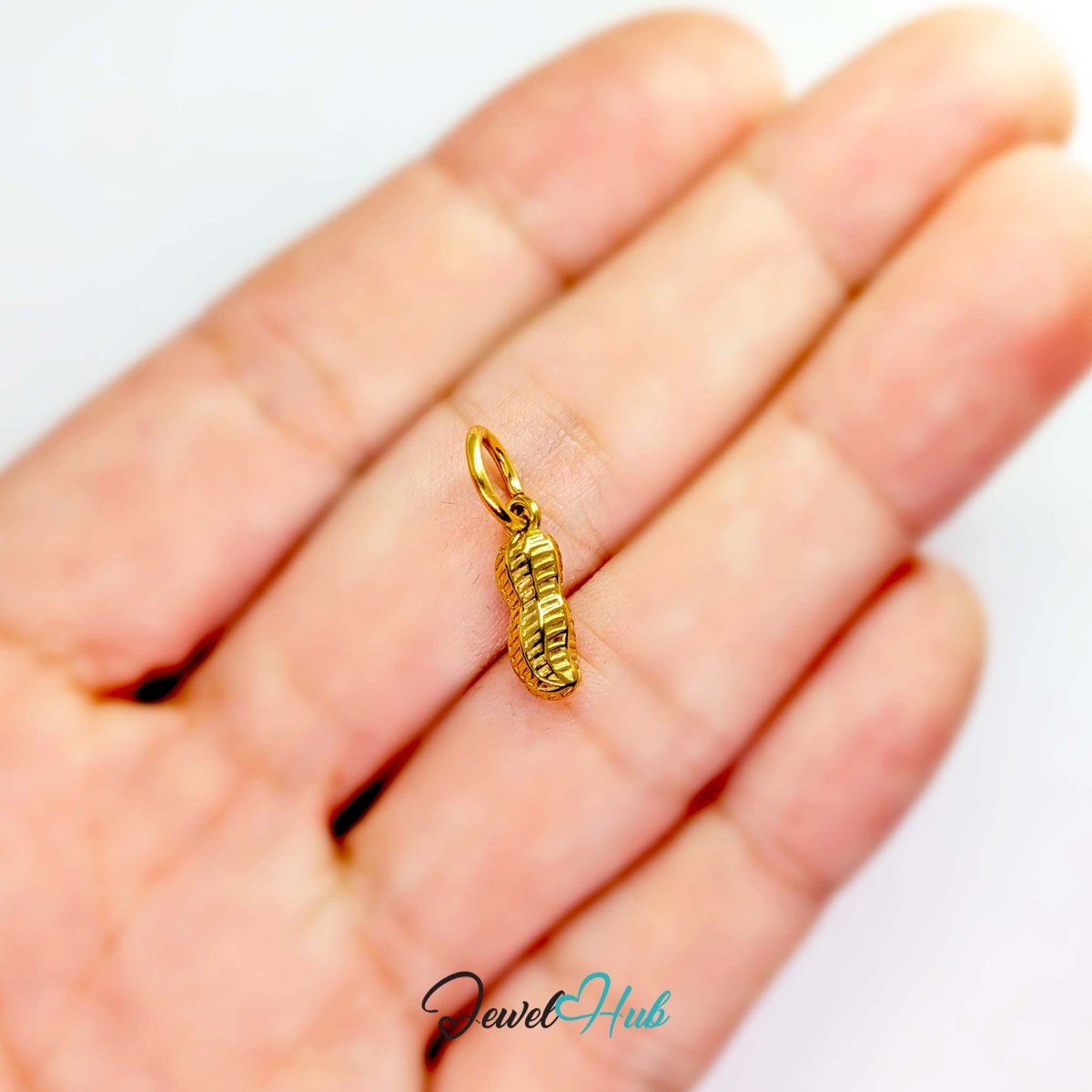 Mini peanut charm in gold stainless steel - held in the hand for scale - JewelHub