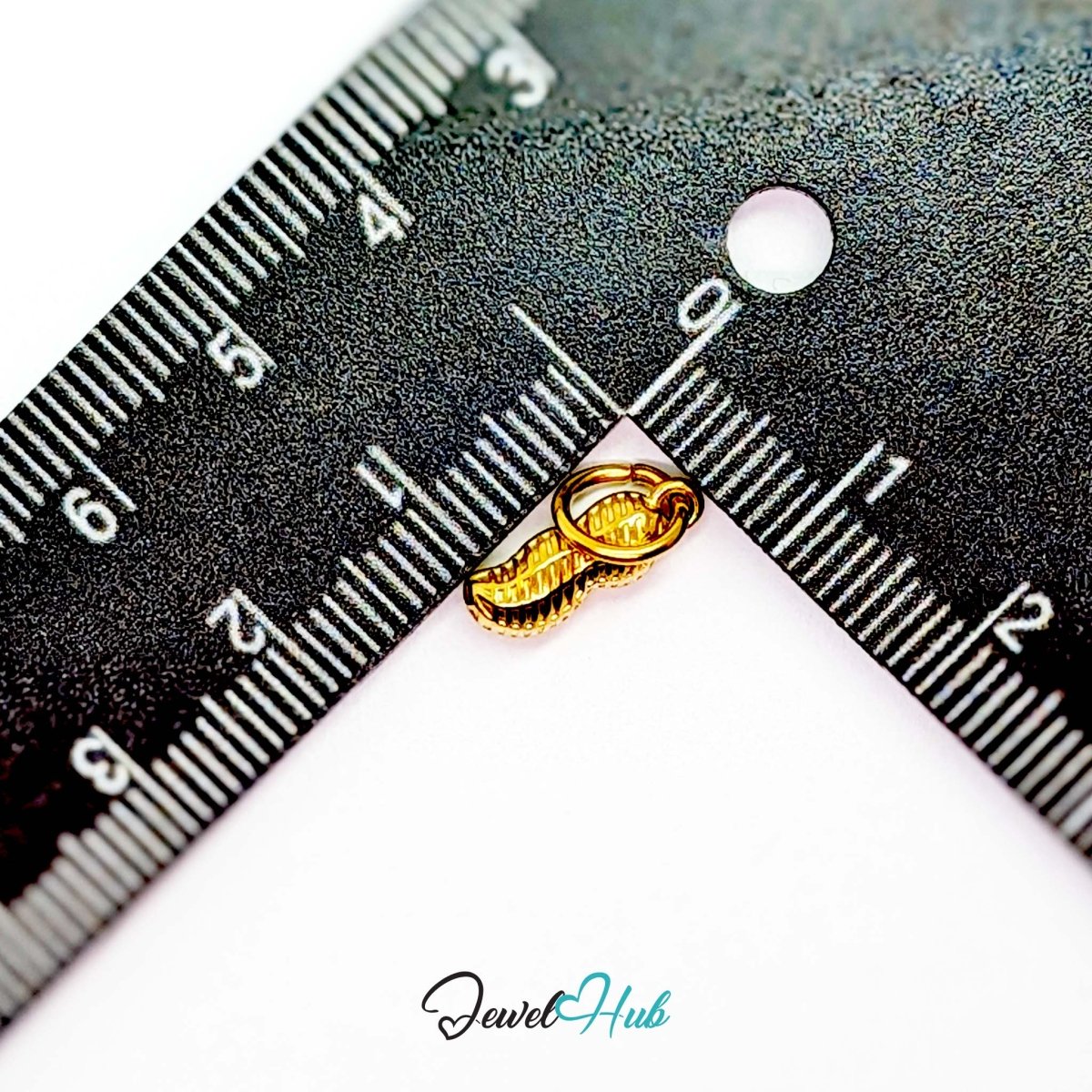 Mini peanut charm in gold stainless steel - beside a ruler for scale - JewelHub