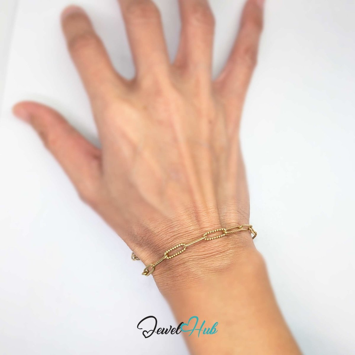 Patterned gold paperclip chain bracelet measured against a ruler to show link size - JewelHub