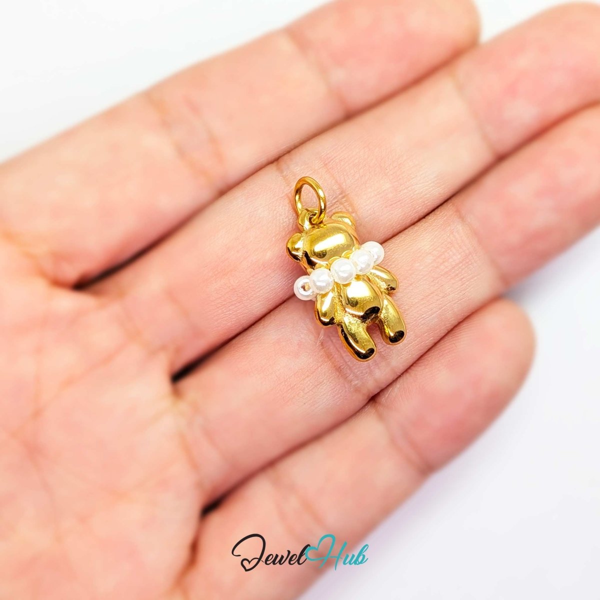 Gold Pearl Collar Bear charm held in the hand to show its size against a fingertip - JewelHub