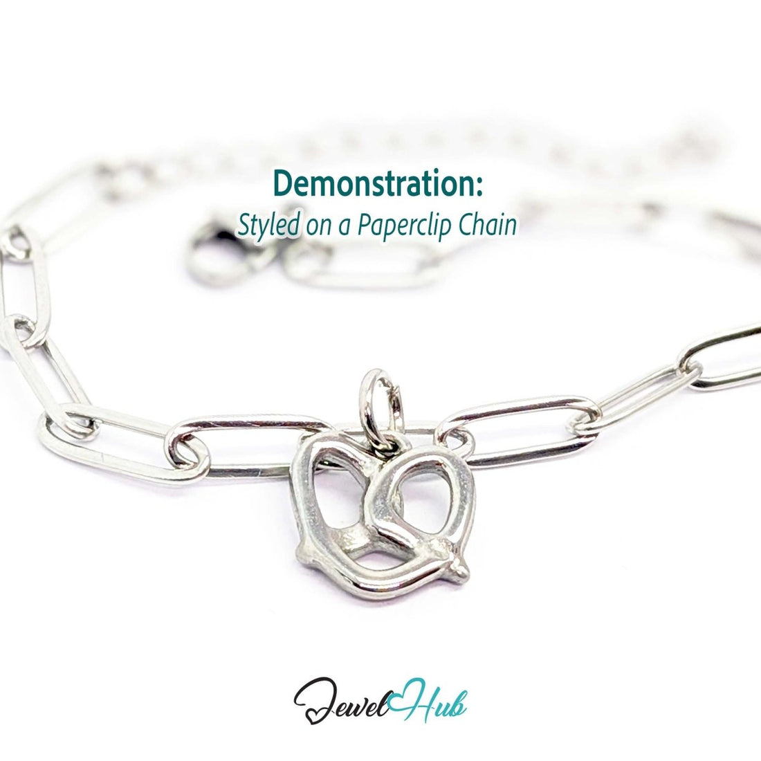 Openwork pretzel charm in silver stainless steel - styled on a silver paperclip chain bracelet - JewelHub
