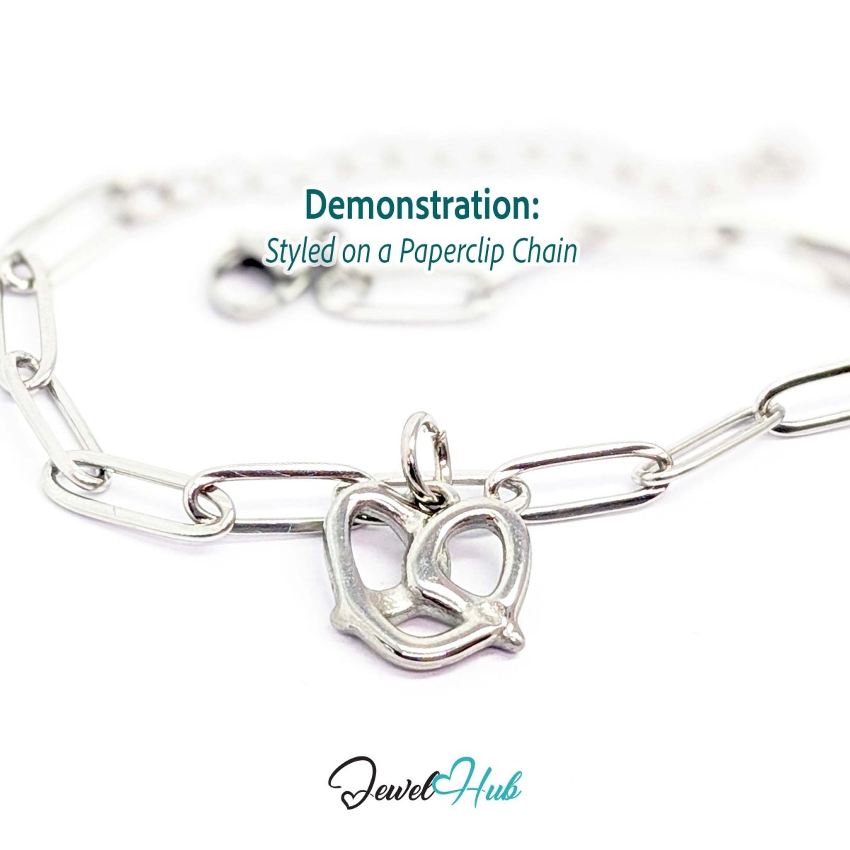 Openwork pretzel charm in silver stainless steel - styled on a silver paperclip chain bracelet - JewelHub