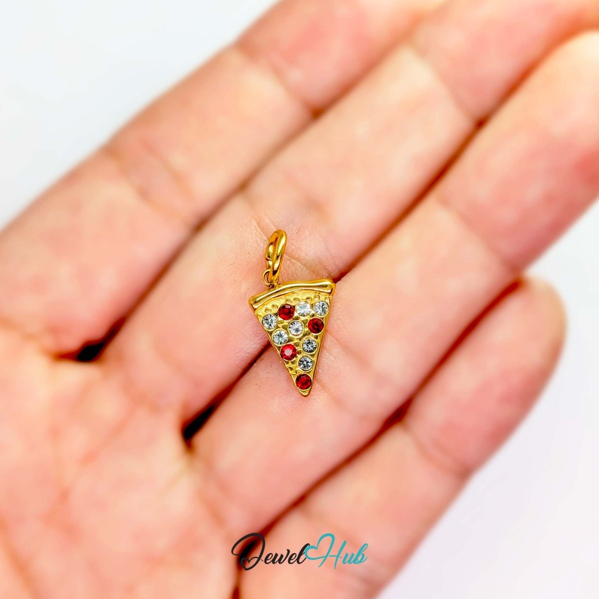 Pizza slice charm in gold stainless steel set with clear and red crystals - held in the hand for scale - JewelHub