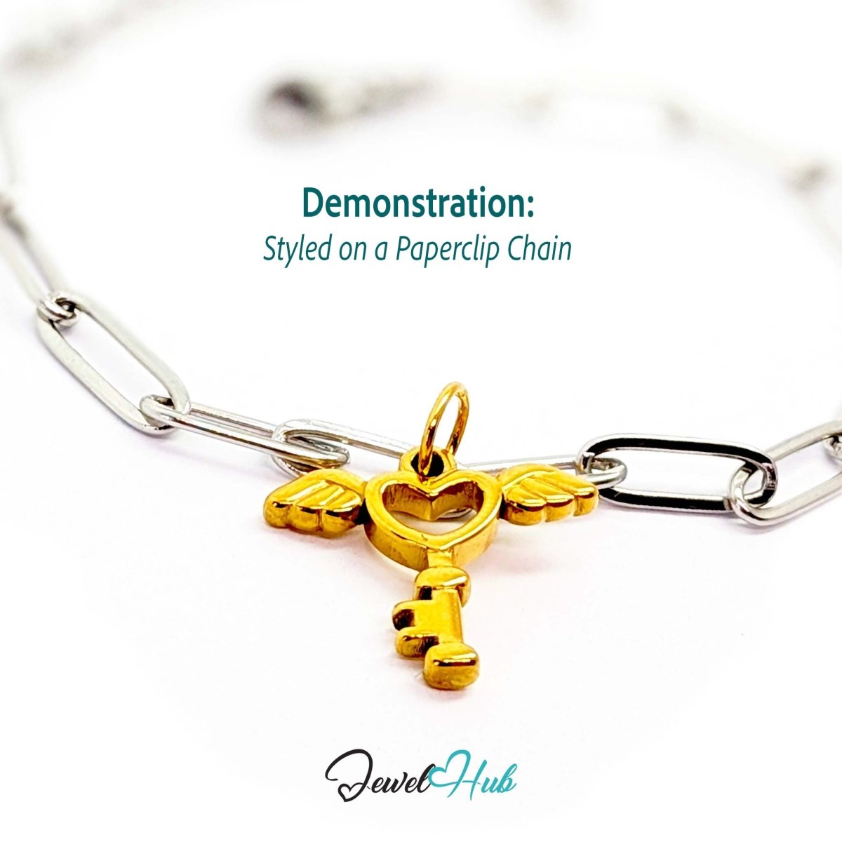 Winged heart key charm in gold stainless steel - styled on a silver paperclip chain bracelet - JewelHub
